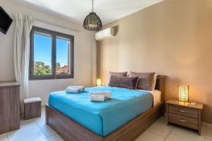 a bedroom with a bed with blue sheets and a window at G.Living 365 in Agia Effimia