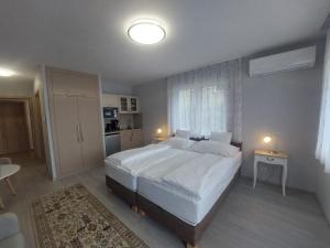 a bedroom with a large white bed and a window at Anton Apartmanház in Balatonfüred
