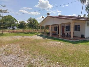 a small white house with a porch and a yard at Hanny Cozy Homestay in Kuala Lipis
