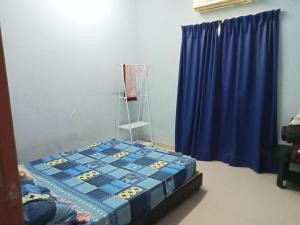 a bedroom with a bed and a blue curtain at Hanny Cozy Homestay in Kuala Lipis