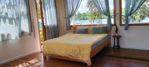 a bedroom with a bed in a room with windows at Nhà Bên Hồ in Bảo Lộc