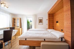 a bedroom with two beds and a desk and a window at Appartamenti Olympic in Santa Cristina Gherdëina