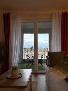 a living room with a couch and a balcony with a table at Ecrin de nacre Appartement de Standing in Courseulles-sur-Mer
