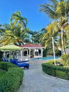 a house with palm trees and a swimming pool at Villas Carela, Villas Privadas con Piscina y Jacuzzi a 2 Minutos de la Playa de Cabarete in Cabarete