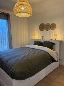 a bedroom with a large bed and a chandelier at Ecrin de nacre Appartement de Standing in Courseulles-sur-Mer