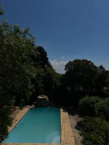 a blue swimming pool with trees in the background at Homely Palace in Midrand