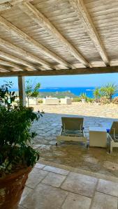 a patio with two lounge chairs and the beach at Villa Ventu di Mari, vista mozzafiato su Caprera e sulle Isole, Piscina Riscaldata in Costa Smeralda in Cannigione