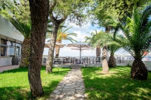 a walkway through a park with palm trees at Hotel Lo Scoglio in Porto Cesareo +24 photos