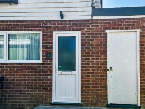 a brick building with a white door and windows at Thirslet in Maldon +3 photos