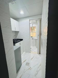 a white kitchen with a sink and a counter at Velmora Cozy 2BR Apartment 20 in Abu Dhabi +11 photos