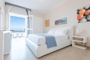 a white bedroom with a bed and a balcony at Hotel Lo Scoglio in Porto Cesareo