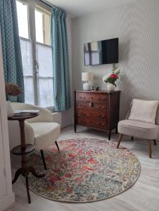 a living room with a chair and a dresser at La loge Diane, à deux pas du château et son jardin à la française in Chantilly