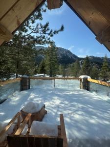 a snow covered patio with a table and trees at Cedar Wood Cabin in Áno Polídhrosos