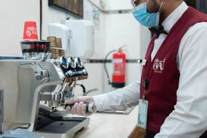 a man wearing a mask in a kitchen with a machine at Al Manara Ewaa Hotel in Mecca