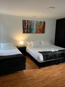 a bedroom with two beds and a painting on the wall at Casa Hotel Estancia Bogota in Bogotá