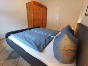 a bed with two blue pillows on top of it at BERNSTEINHAUS in Zingst barrierefreie 2-Raum-Wohnung mit Terrasse - Nr 1 in Zingst