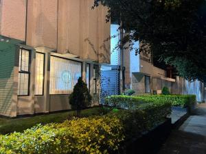a building with a tree and bushes in front of it at Casa Hotel Estancia Bogota in Bogotá +16 photos