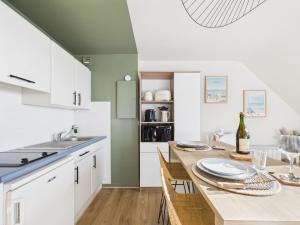 a kitchen with white cabinets and a wooden table with chairs at L îlot d Arthur in Île-Tudy