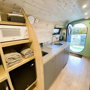 a kitchen in a caravan with a sink and a microwave at Highland Gateway Glamping in Clackmannan