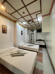 a room with three beds in a room at Austrias Guest House in El Nido