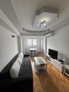 a living room with a black couch and a tv at Apartman Harmony in Ohrid
