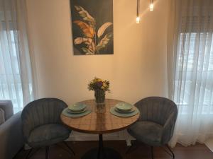 a table with two chairs and a vase of flowers on it at Azure Living Apartman in Kragujevac +3 photos