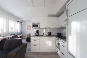 a kitchen with white cabinets and a couch at Pramea Apartments Tourula in Jyväskylä +12 photos