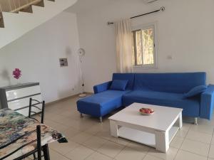 a living room with a blue couch and a table at Le Dolmen de Mbour in Mbour