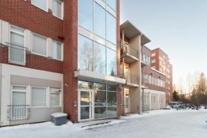 an apartment building with glass windows on a snowy street at Pramea Apartments Tourula in Jyväskylä