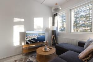 a living room with a blue couch and a tv at Pramea Apartments Tourula in Jyväskylä