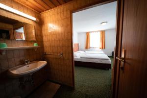 a bathroom with a sink and a bed in a room at Hotel Tauernpasshöhe in Obertauern