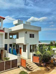 a large white house with the ocean in the background at Murthy Surf School in Covelong