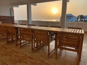 a wooden table with chairs and a large wooden table at Murthy Surf School in Covelong