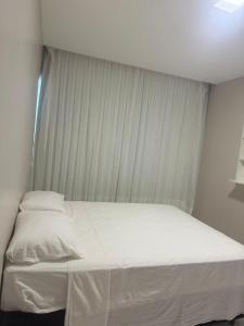 a bed in a room with white sheets and curtains at Casa da Maré Pé na areia Suítes climatizadas e deck vista mar in Icapuí +11 photos