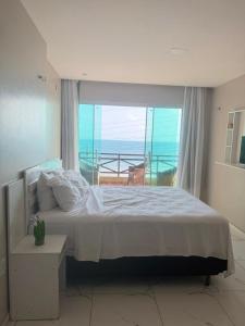 a bedroom with a bed with a view of the ocean at Casa da Maré Pé na areia Suítes climatizadas e deck vista mar in Icapuí