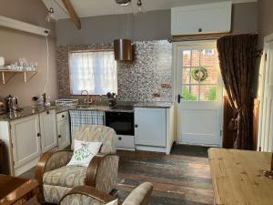 a kitchen with white cabinets and a table with chairs at Deco Artist Cottage in Tytherton Lucas