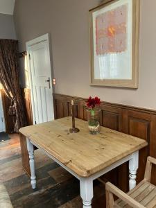 a wooden table with a vase of flowers on it at Deco Artist Cottage in Tytherton Lucas +4 photos