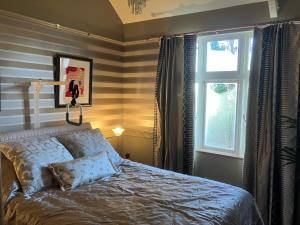 a bedroom with a bed and a window at Deco Artist Cottage in Tytherton Lucas