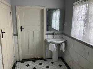 a white bathroom with a sink and a mirror at Deco Artist Cottage in Tytherton Lucas