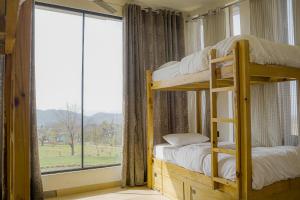 a bedroom with bunk beds and a large window at Qudrat - Boutique Hostel & Cafe in Bīr