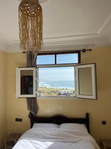 a bedroom with a bed and a large window at Ocean Nomads hostel Taghazout in Taghazout
