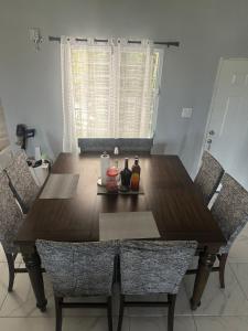 a wooden dining table with two chairs and bottles on it at Hector residence in Saint Johnʼs