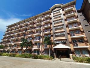 a large building with palm trees in front of it at Puerto Princesa Studio Condo with 2 Large Beds, Balcony, Pool & Gym in Puerto Princesa City