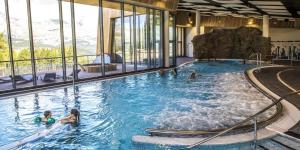 a large swimming pool with people in the water at T2 cosy 4 pers balcon vue montagne la Joue du loup in Le Dévoluy