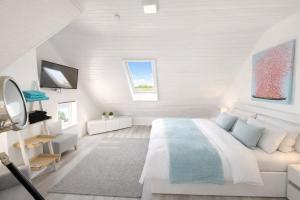 a white bedroom with a bed and a tv at "Huus ant Diek", Ferienhaus mit Maisonette Wohnung in Deichnähe, Nähe Norddeich in Norden