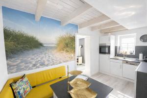 a living room with a yellow couch and a view of the beach at "Huus ant Diek", Ferienhaus mit Maisonette Wohnung in Deichnähe, Nähe Norddeich in Norden