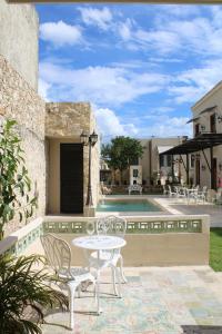 Eine Terrasse mit Tisch und Stühlen neben einem Pool in der Unterkunft Casa Ku'x in Mérida