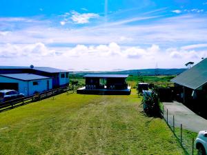 a group of buildings on a field with a grass yard at Seascape Peninsula Bach in Kaitaia