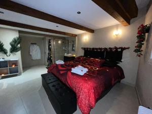a bedroom with a large bed with a red comforter at Le Cocon SPA Évasion Privée - jacuzzi - in Lunel
