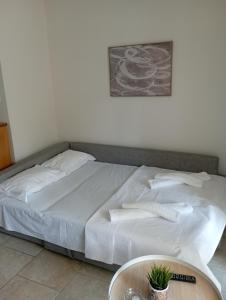 a bed with white sheets and a table in a room at Apartment Akanthous in Kallithea Halkidikis